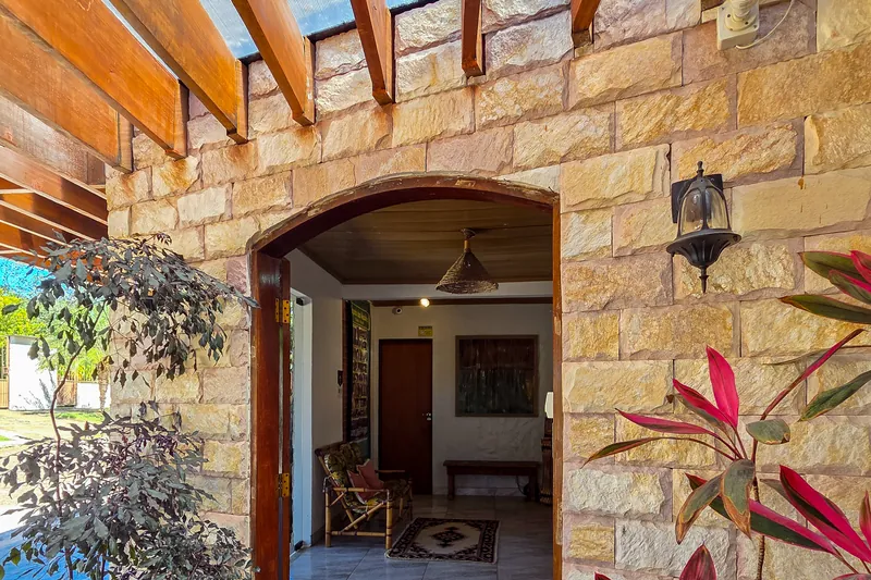 Entrada da pousada, em pedra, com o jardim ao redor
